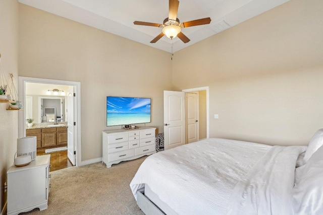 bedroom with light carpet, ensuite bathroom, a sink, a high ceiling, and baseboards