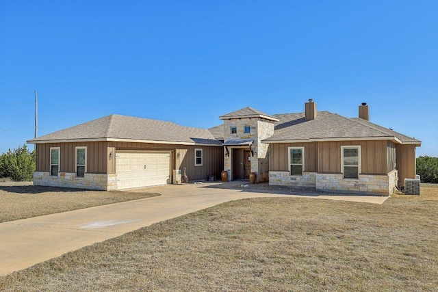 view of front of property with an attached garage, cooling unit, stone siding, and a chimney