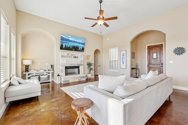 living room with arched walkways, plenty of natural light, baseboards, and ceiling fan