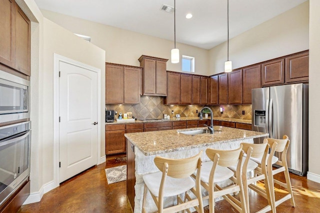 kitchen featuring visible vents, a sink, appliances with stainless steel finishes, decorative light fixtures, and tasteful backsplash