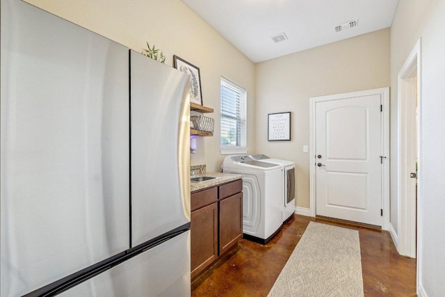 laundry area featuring baseboards, visible vents, cabinet space, a sink, and washer and clothes dryer