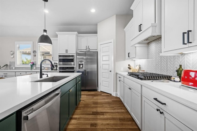 kitchen with a sink, stainless steel appliances, white cabinetry, and light countertops