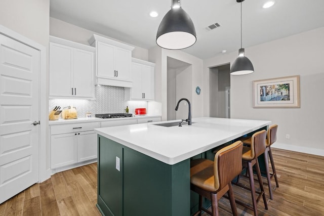 kitchen with decorative backsplash, white cabinetry, light wood-style floors, and a sink