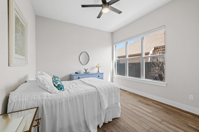 bedroom with a ceiling fan, wood finished floors, and baseboards