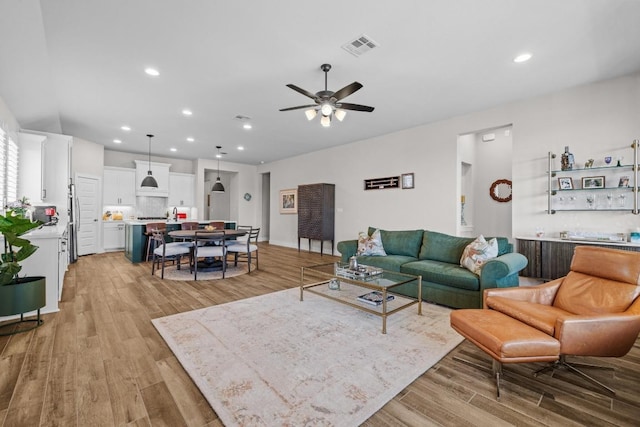 living area with light wood finished floors, visible vents, recessed lighting, and ceiling fan