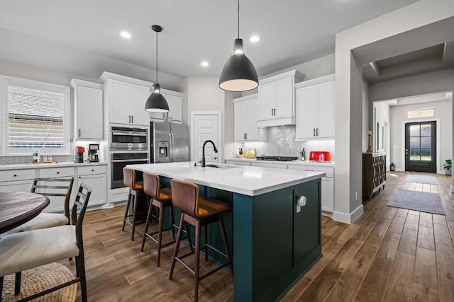 kitchen featuring dark wood finished floors, white cabinets, appliances with stainless steel finishes, and a sink