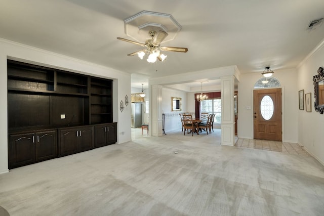 unfurnished living room featuring visible vents, crown molding, light colored carpet, decorative columns, and ceiling fan with notable chandelier