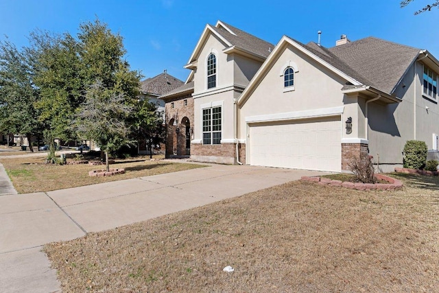 traditional-style home featuring a garage, concrete driveway, a front yard, and stucco siding