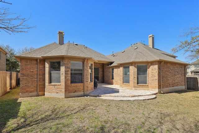 rear view of house with a patio, brick siding, roof with shingles, and a chimney