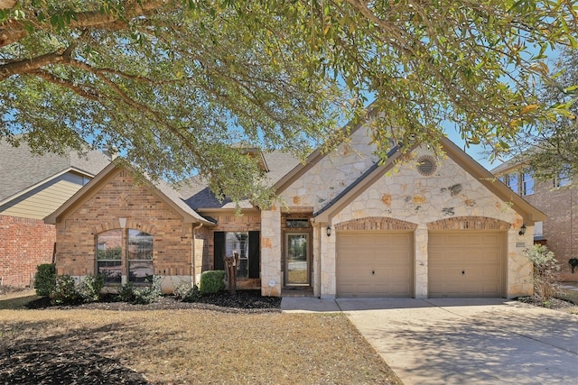 view of front of house with driveway, stone siding, an attached garage, a shingled roof, and brick siding