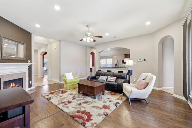 living room featuring wood finished floors, arched walkways, and ceiling fan