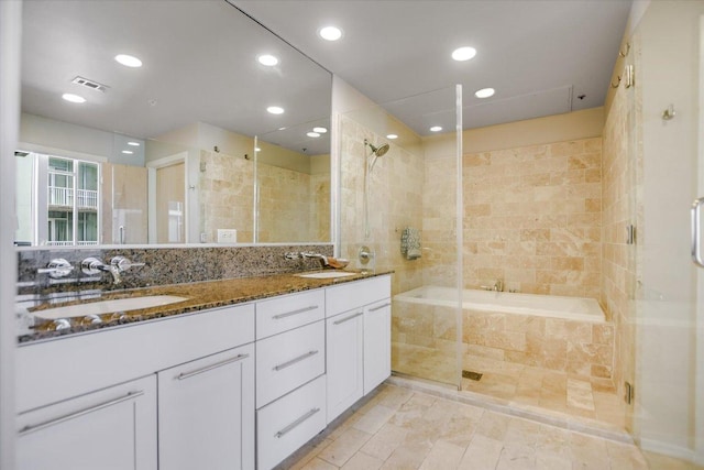 bathroom featuring double vanity, tiled shower, visible vents, and a sink