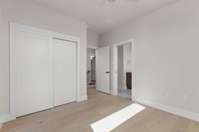 unfurnished bedroom featuring connected bathroom, light wood-style floors, a closet, and baseboards