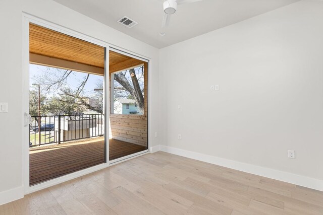 empty room with light wood-style flooring, visible vents, and baseboards