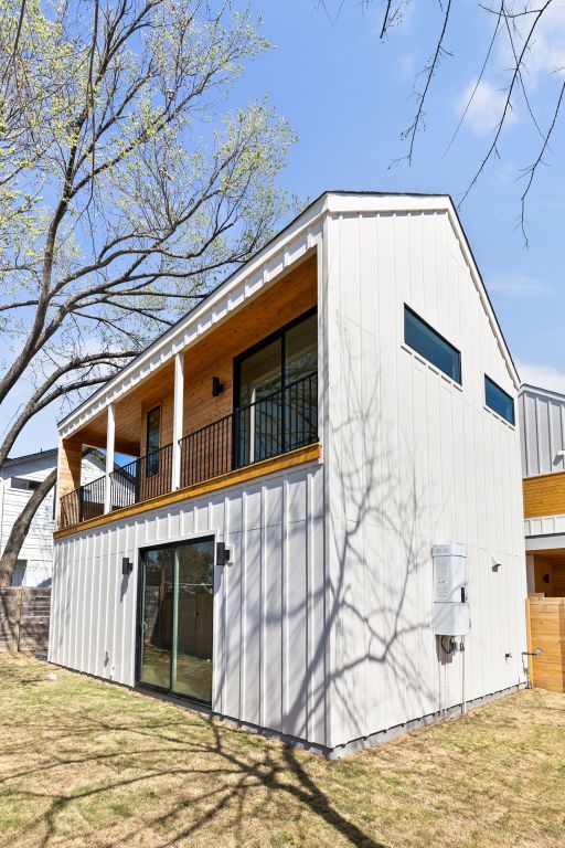 rear view of property with a yard, board and batten siding, and a balcony