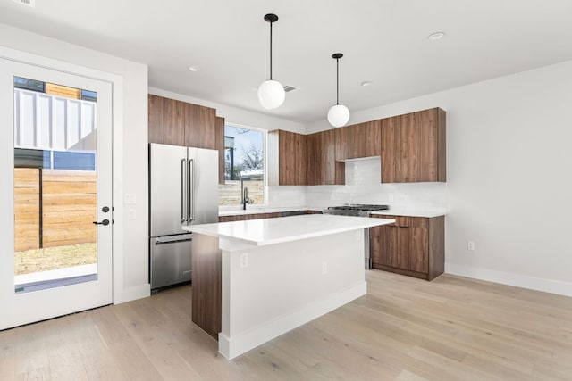 kitchen with backsplash, a kitchen island, light countertops, stainless steel appliances, and modern cabinets