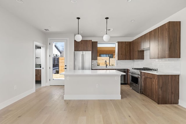 kitchen featuring light countertops, high end appliances, light wood finished floors, and a kitchen island