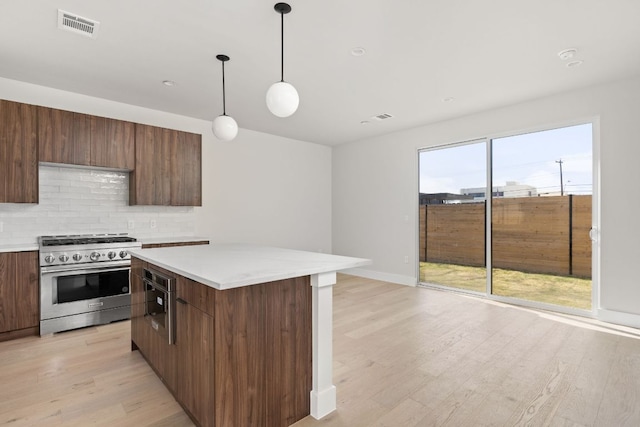 kitchen featuring tasteful backsplash, visible vents, light countertops, modern cabinets, and high end stainless steel range