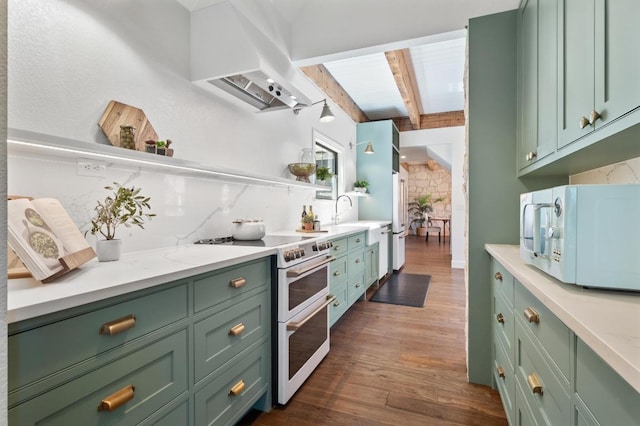 kitchen with wall chimney range hood, green cabinetry, beam ceiling, white appliances, and dark wood-style flooring