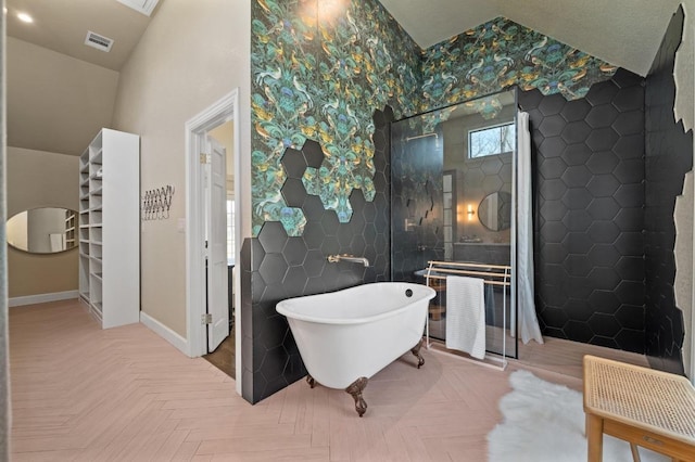 bathroom featuring tile walls, a freestanding tub, baseboards, and visible vents