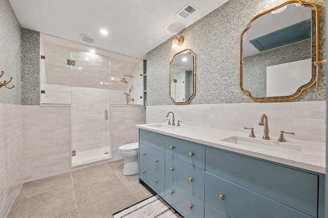 full bathroom with a sink, tile walls, wainscoting, and wallpapered walls