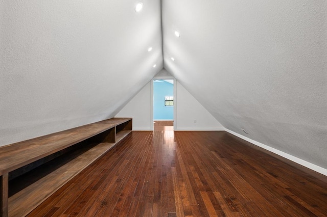 additional living space featuring baseboards, lofted ceiling, and dark wood-style floors