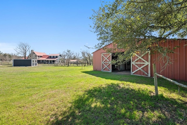 view of yard featuring a barn, an outdoor structure, and fence