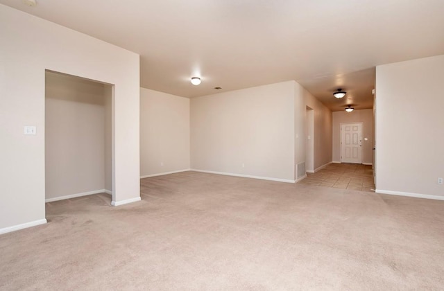 spare room with visible vents, baseboards, and light colored carpet