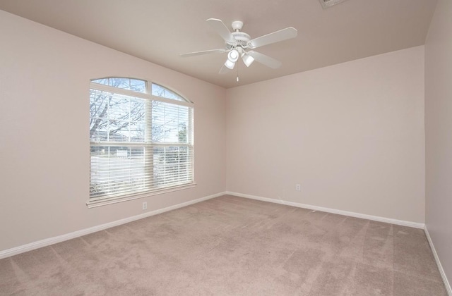 spare room with visible vents, baseboards, light colored carpet, and a ceiling fan