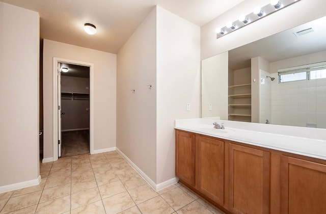 bathroom featuring vanity, visible vents, baseboards, a tile shower, and tile patterned flooring