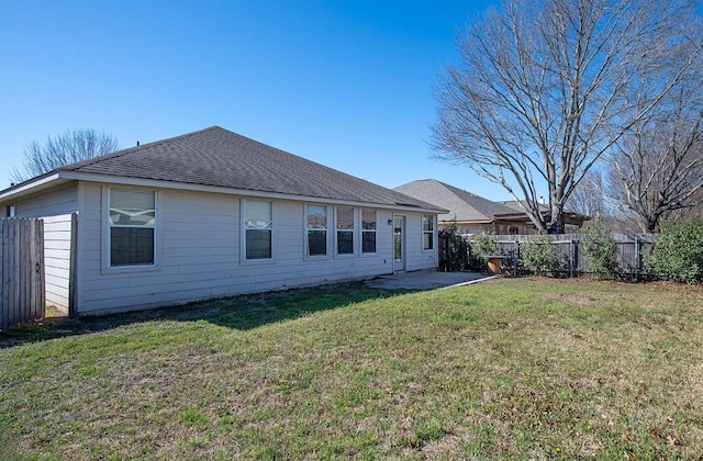 back of property featuring a lawn, a patio, roof with shingles, and fence