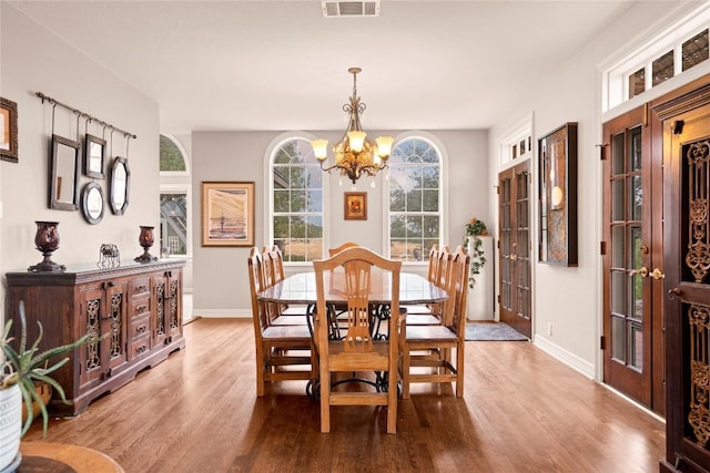 dining area with visible vents, baseboards, a notable chandelier, and wood finished floors