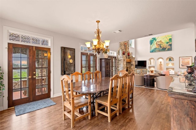 dining space with a notable chandelier, visible vents, french doors, and wood finished floors