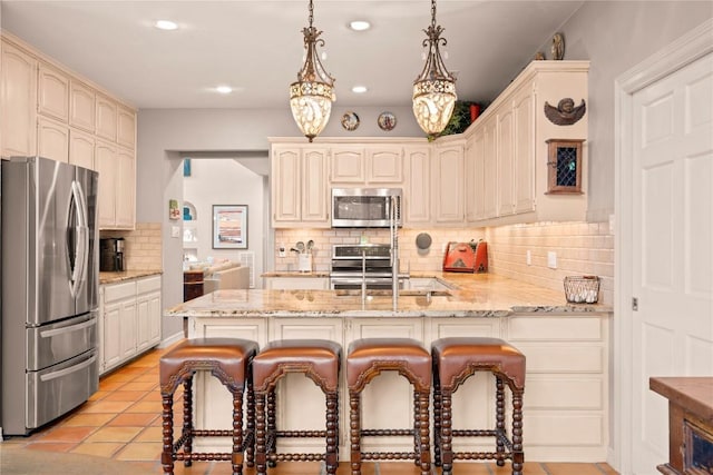 kitchen featuring a kitchen breakfast bar, appliances with stainless steel finishes, a peninsula, light tile patterned flooring, and a sink