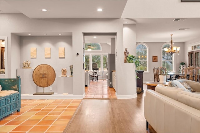 living room featuring baseboards, visible vents, light wood finished floors, recessed lighting, and a chandelier