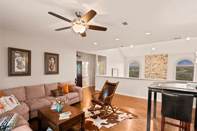 living area with baseboards, wood finished floors, visible vents, and ceiling fan