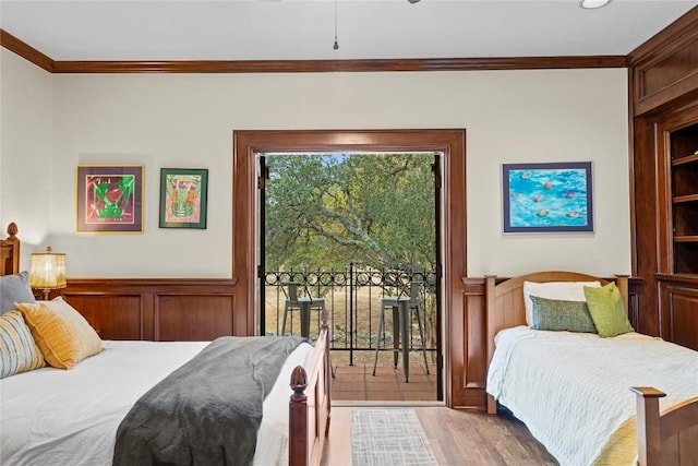 bedroom featuring wainscoting, wood finished floors, crown molding, and access to outside