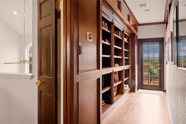 hallway featuring visible vents, crown molding, and wood finished floors