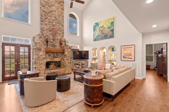 living room with wood finished floors, visible vents, a fireplace, ceiling fan, and french doors