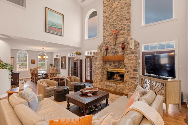 living area with a fireplace, baseboards, an inviting chandelier, and wood finished floors