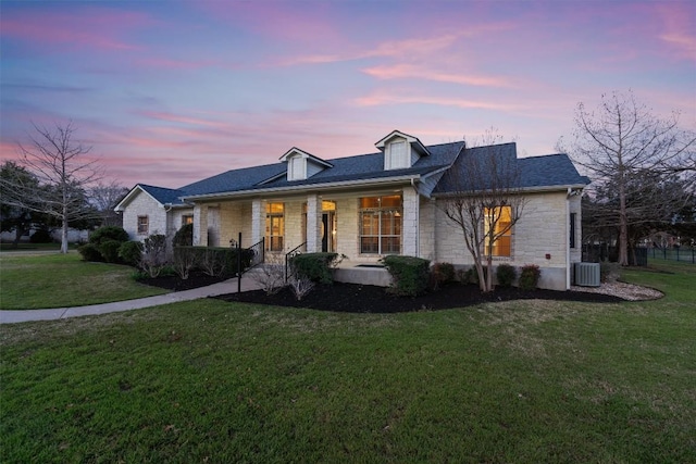 view of front of house featuring stone siding, a yard, central air condition unit, and a porch