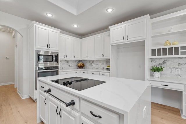 kitchen with light wood finished floors, appliances with stainless steel finishes, arched walkways, white cabinetry, and open shelves