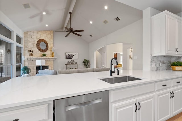 kitchen with a sink, stainless steel dishwasher, open floor plan, arched walkways, and ceiling fan