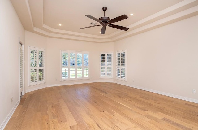 spare room featuring baseboards, light wood finished floors, recessed lighting, ceiling fan, and a raised ceiling