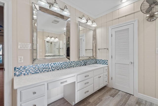 bathroom with visible vents, wood finished floors, vanity, and ornamental molding