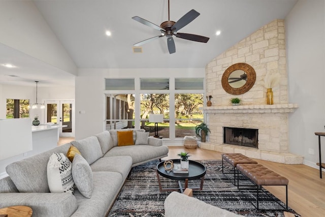 living area featuring a stone fireplace, french doors, wood finished floors, high vaulted ceiling, and a ceiling fan