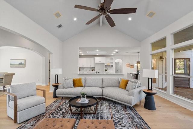 living area featuring ceiling fan, visible vents, arched walkways, and light wood-style flooring