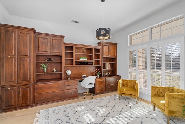 home office with light wood-style flooring, visible vents, and built in study area