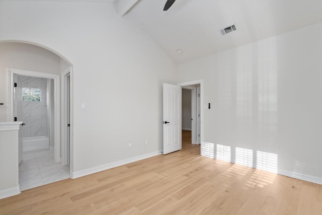 unfurnished room featuring a ceiling fan, arched walkways, light wood finished floors, and high vaulted ceiling