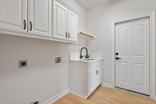 washroom with light wood-type flooring, washer hookup, cabinet space, electric dryer hookup, and a sink